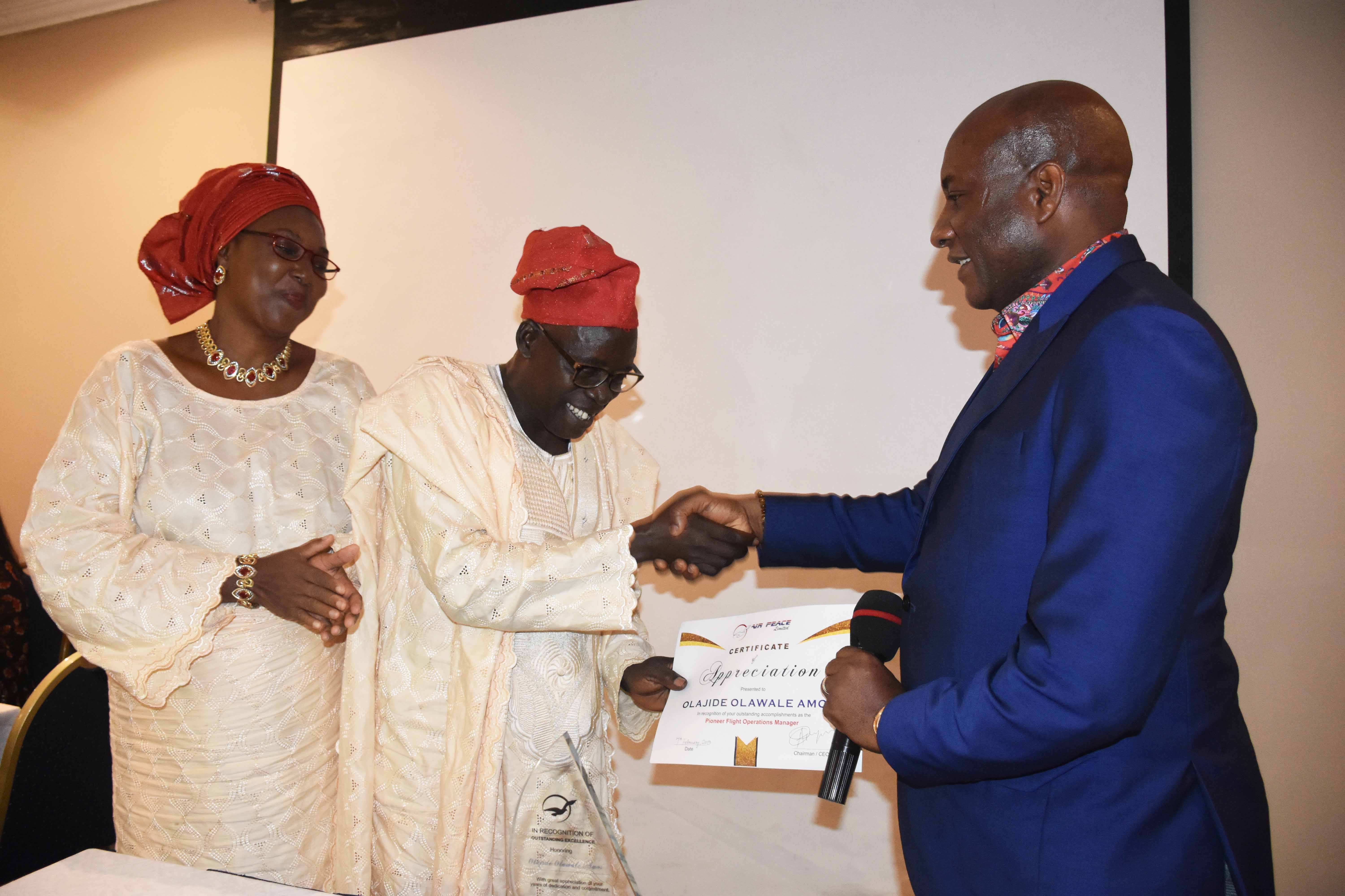 Air Peace Chairman/Chief Executive Officer, Mr. Allen Onyema (right) presenting a certificate and plaque to the airline’s pioneer Flight Operations Manager, Mr. Olawale Amos Olajide in appreciation of the latter’s service to the carrier, while Mrs. Paulina Olajide applauds during a retirement reception by Air Peace in honour of Olajide in Lagos on Thursday